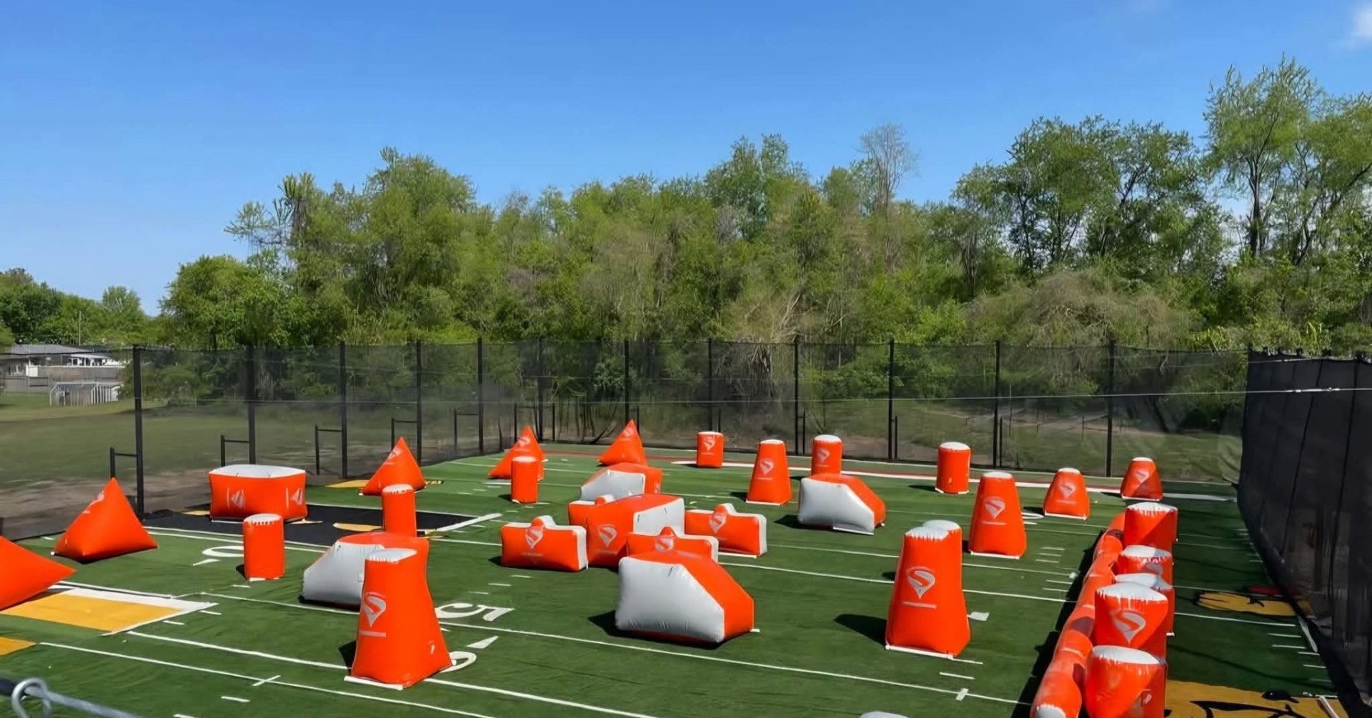 Outdoor speedball field with orange bunkers, sunny day